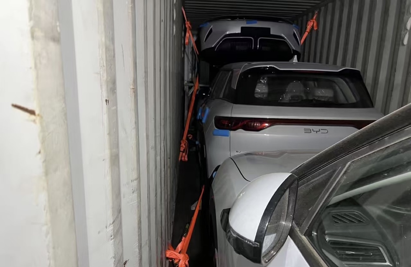 Two vehicles racked inside a single container for export shipping